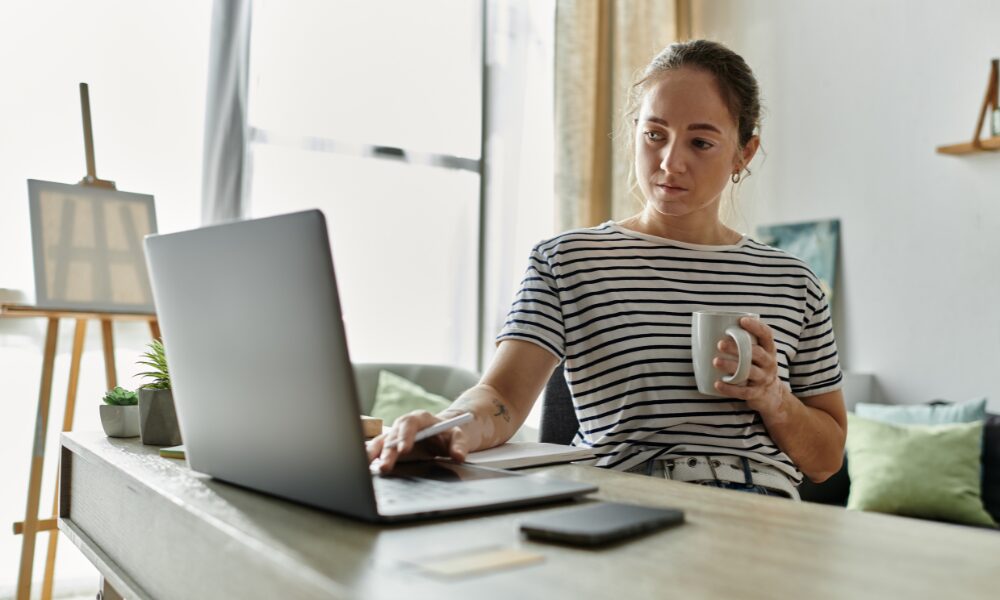 Woman reviewing tenancy paperwork at home with a laptop and mug, representing landlords preparing for Renters’ Rights Act compliance changes.