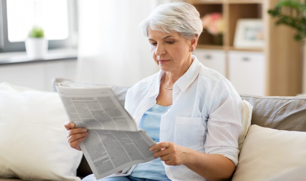 Landlord sitting on a sofa reading paperwork while considering ending a tenancy to sell a property or move back in
